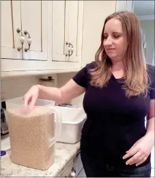  ?? TIMES photograph by Annette Beard ?? Karen Berndt, owner of Karen’s Gourmet Popcorn, scoops popcorn kernels to pop as the first step in preparing her original flavors of popcorn.