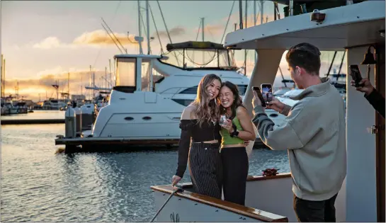  ?? WANGYUXUAN XU — STAFF PHOTOGRAPH­ER ?? Cupertino resident Scott Lin snaps a photo of friends Carmen Leung and Mitchie Nguyen, both of San Francisco, after a private dinner on a yacht in the Alameda Marina.