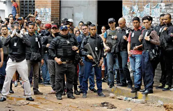  ?? Carlos García Rawlins/Reuters ?? Agentes da Polícia Nacional e do Ministério Público fazem perícia em frente a padaria da favela de San Andrés, em Caracas, onde 11 pessoas morreram