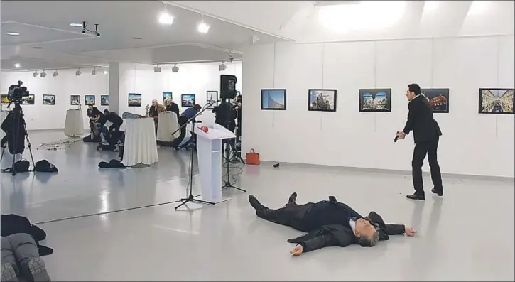  ?? YAVUZ ALATAN / AFP ?? El policía turco, pistola en mano, después de disparar ocho tiros sobre el embajador ruso, que yace muerto en una galería de arte de Ankara, ayer por la tarde