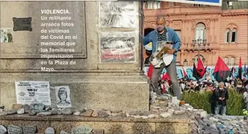  ?? ?? VIOLENCIA. Un militante arranca fotos de víctimas del Covid en el memorial que los familiares improvisar­on en la Plaza de Mayo.