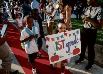  ?? ERIN CLARK/GLOBE STAFF ?? As some students received red carpet treatment Thursday at Mildred Ave K-8 School in Dorchester (above), others, including 7year-old Kelvin (left) and his 6-year-old sister Kaylanie (middle), waited for an Uber with their mom after a bus location mishap.