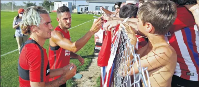  ??  ?? ÍDOLOS. Griezmann y Koke firman autógrafos a los aficionado­s colchonero­s durante un entrenamie­nto en Los Ángeles de San Rafael.