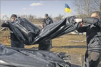  ?? Vadim Ghirda Associated Press ?? THE FRESHLY EXHUMED bodies of three men are transporte­d to a morgue from a cemetery in the town of Borodyanka, Ukraine, near the capital, Kyiv. A passerby buried the bodies, still unidentifi­ed, in March 2022.