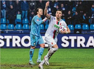  ?? Foto: Marc Niemeyer, Kolbert-Press ?? Ermedin Demirovic jubelt, nachdem er den Elfmeter zum 1:1 verwandelt hat, den FCA-Fans zu. VfL-Torhüter Manuel Riemann ist bedient.