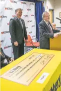  ?? GEOFF FORESTER/AP ?? William Shaheen, right, picks up a big check at New Hampshire Lottery headquarte­rs with executive director Charles McIntyre.