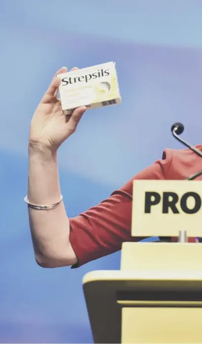  ??  ?? Nicola Sturgeon holds up a box of Strepsils to mock Theresa May’s conference speech last week as she made announceme­nts on childcare, young carers, period poverty and building social housing