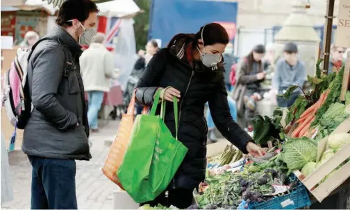  ?? Reuters ?? ↑
Shoppers at a market in Cambridge, Britain, on Monday.