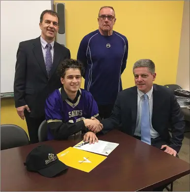  ?? Photos by Brendan McGair and Ernest A. Brown ?? St. Raphael senior Xavier Torres (sitting, left) is joined by SRA football head coach Mike Sassi (shaking hands with Torres), Principal Dan Richard (back row, left), and athletic director Ray Tanguay (back row, right) during a signing ceremony last...