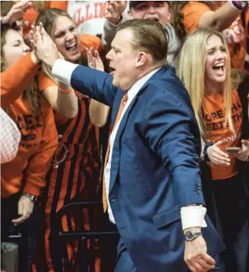  ?? HOLLY HART/AP ?? Illinois coach Brad Underwood highfives fans at State Farm Center after his team’s victory against Iowa on Sunday.