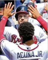  ?? CURTIS COMPTON / CCOMPTON@AJC.COM ?? Braves first baseman Freddie Freeman gets a double high-five from Ronald Acuna Jr. after Freeman hit a two-run homer against the Cardinals on Wednesday.