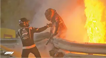  ??  ?? Haas’ French driver Romain Grosjean (right) escapes from his car engulfed in a fireball after crashing against a barrier during the Bahrain GP on Sunday