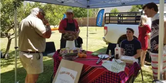  ??  ?? A customer sampling the Lacon (Karoo lamb bacon) made by farmer Joe Kroon of Karri Grove, with his son Ben and Jason Wright looking on.