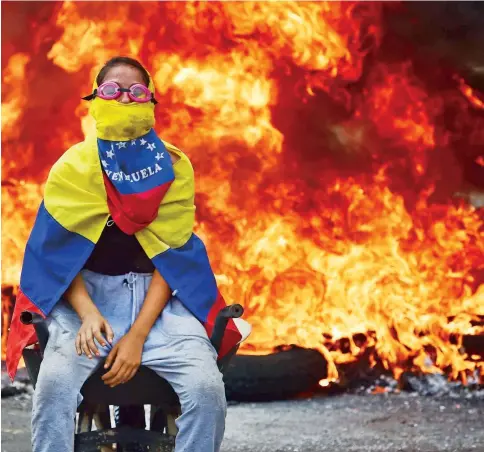  ??  ?? Una activista de la oposición venezolana posa con una barricada en llamas durante una protesta contra el gobierno del presidente Nicolás Maduro el pasado 24 de abril. El país lleva más de un mes con manifestac­iones todos los días como medida de presión...