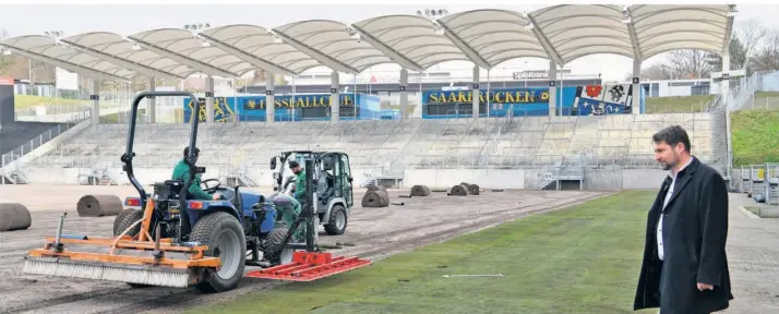  ?? FOTOS: BECKERBRED­EL ?? Der Saarbrücke­r Oberbürger­meister Uwe Conradt (CDU) schaut zu, wie der neue Rasen im Ludwigspar­kstadion verlegt wird. Schon am kommenden Sonntag soll das neue Grün bespielt werden können.