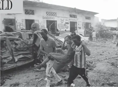  ?? FARAH ABDI WARSAMEH / THE ASSOCIATED PRESS ?? Somalis carry away a man injured by a car bomb at a hotel in Mogadishu, Somalia on Saturday. The attack, which killed 23, as well as one two weeks ago that killed 350 on a city street, has shaken public confidence in the military.