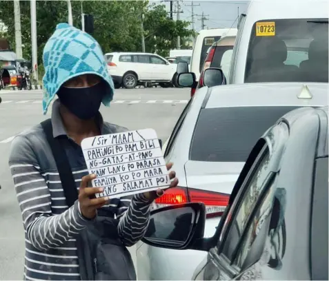  ?? - Chris Navarro ?? MENDICANT. Holding a sign bearing his message, a man begs for alms from motorists passing along the busy GSO road in Guagua, Pampanga.