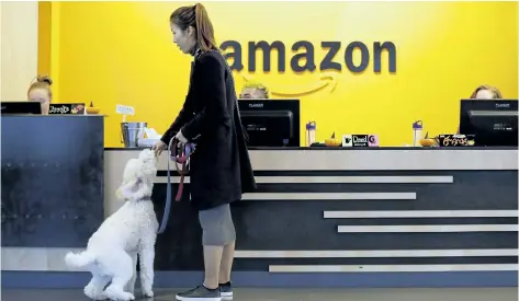  ?? ELAINE THOMPSON/THE ASSOCIATED PRESS ?? An Amazon employee gives her dog a biscuit as the pair head into a company building in Seattle, Wash. Amazon says it received 238 proposals from cities and regions in Canada, the U.S. and Mexico that hope to be the home of the company’s second...