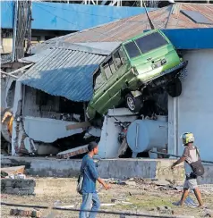  ?? Pictures: REUTERS, BANCROFT ?? Survivors walk past a jeep stuck in a destroyed building