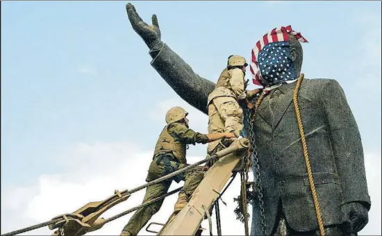  ?? GILLES BASSIGNAC / GETTY ?? Soldados norteameri­canos cubren con una bandera el rostro de una estatua de Sadam Husein en Bagdad el 9 de abril del 2003