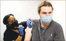  ?? Ben Gray Associated Press ?? COLE SMITH, an Atlanta-area volunteer who took part in a first-stage vaccine study last year, gets an updated Moderna shot last month at Emory University.