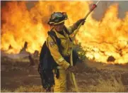  ?? THE ASSOCIATED PRESS ?? A firefighte­r makes a stand in front of a wildfire as it approaches a residence Saturday in Redding, Calif.