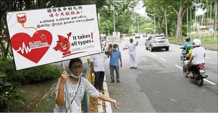  ?? — ZHaFaRan naSIB/The Star ?? Precious fluid: Volunteers holding up placards to remind motorists to stop by along Jalan utama in George Town.