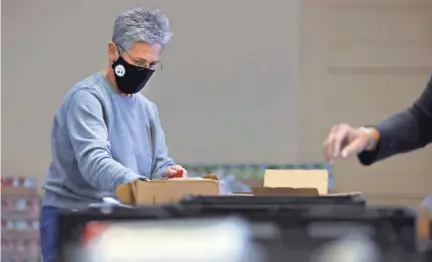  ?? JOE RONDONE/THE COMMERCIAL APPEAL ?? Carol Bigam prepares food boxes inside St. Anne Church that are given away Monday through Thursday every week for low-income families in need.