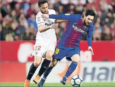  ?? AITOR ALCALDE / GETTY ?? Lionel Messi protege un balón ante la oposición del jugador del Sevilla Franco Vázquez