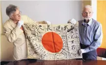  ?? DON RYAN/ASSOCIATED PRESS ?? World War II veteran Marvin Strombo, right, and Obon Society executive director Rex Zika hold a Japanese flag with names written on it Aug. 7 in Portland, Ore.