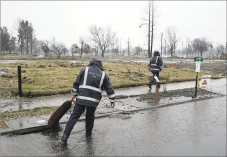  ?? ERIC RISBERG — ASSOCIATED PRESS ?? A firefighte­r checks on a clogged storm drain in the wildfire damaged Coffey Park neighborho­od of Santa Rosa. Storms brought rain to California on Monday and increased the risk of mudslides and flooding in fire-ravaged communitie­s in the Wine Country...