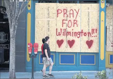  ?? MATT BORN — THE STAR-NEWS VIA AP ?? People walk by the boarded-up front windows of Bourbon Street in preparatio­n for Hurricane Florence in Wilmington, N.C., on Wednesday. The effects of the hurricane in southeaste­rn North Carolina are expected to begin today.