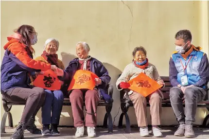  ??  ?? As a juweihui volunteer, Andy hands out handwritte­n 㑃 (good fortune) characters painted on red paper for Chinese New Year and enjoys chatting with elderly residents. — Zhou Shengjie