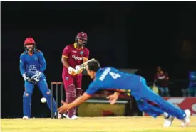  ??  ?? ST KITTS: Evin Lewis (C) of West Indies attempts to hit past Amir Hamza (R) as Shafiqulla­h Shafaq (L) of Afghanista­n watches during the 3rd and final T20i match between West Indies and Afghanista­n at Warner Park, Basseterre, St. Kitts, Monday. — AFP