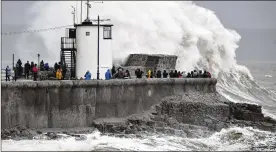  ?? BEN BIRCHALL / PA ?? People watch waves and rough seas pound against the harbour wall at Porthcawl in Wales on Saturday as Storm Dennis sweeps across the country.