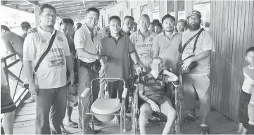  ??  ?? Kelvin (third left) hands over a wheelchair and a mobile toilet to an elderly man. Tie is at left, while Dr Azlee is at right.