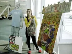  ?? Pam Panchak/Post-Gazette ?? Amy Scafuri is flanked by a Randy Gilson cutout and a painting he made for the Randyland pop-up at the Pittsburgh Home &amp; Garden Show.