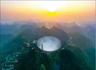  ?? PHOTOS BY OU DONGQU / XINHUA ?? Above: A bird’s-eye view of the Five-hundred-meter Aperture Spherical Radio Telescope, the world’s largest filled-aperture and most sensitive radio telescope, is seen on Wednesday. The facility, in Pingtang county, Guizhou province, officially opened for use by scientists around the world starting Wednesday.
Left: A researcher works in the control office of the telescope on Saturday.
