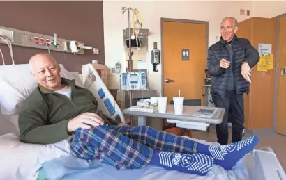 ?? MARK HOFFMAN/MILWAUKEE JOURNAL SENTINEL ?? Pulmonolog­ist Glenn Ragalie (right) says goodbye to former colleague and cardiologi­st turned hospice physician Bruce Wilson (foreground) after visiting Jan. 16 at Froedtert Hospital in Wauwatosa. Wilson has end-stage pancreatic cancer.