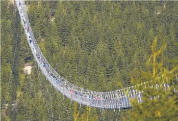  ?? PETR DAVID JOSEK/AP ?? Pedestrian­s cross a suspension bridge shortly after its official opening Friday at a mountain resort in Dolni Morava, Czech Republic. The bridge, which is the longest structure of its kind in the world at more than 2,300 feet long and strung at an altitude more than 3,600 feet above sea level, affords those who traverse the span views of a valley 311 feet below.