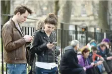  ?? — AFP ?? Bystanders listen and watch on their mobile phones as Scotland’s First Minister Nicola Sturgeon speaks in Edinburgh on Monday.