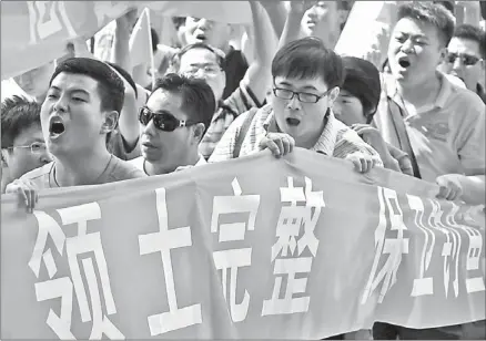  ?? DAVID GRAY / REUTERS ?? Demonstrat­ors hold banners (territoria­l integrity and protection of Diaoyu Islands in Chinese) and chant slogans as they protest outside the Japanese embassy in Beijing on Wednesday.