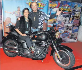  ?? FOTO: URSULA DÜREN/DPA ?? Der Schauspiel­er Wolfgang Fierek und seine Frau Djamila posieren mit einer Harley-Davidson.