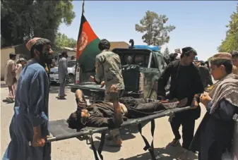  ?? Noor Mohammad / AFP / Getty Images ?? Afghan men carry a victim of a car bomb in Lashkar Gah, the capital of Helmand province. The blast occurred as Afghan troops and government workers waited in line to collect their pay.