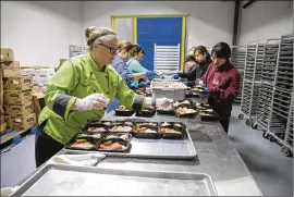  ?? DEBORAH CANNON / AMERICAN-STATESMAN ?? Chef Kim Granato at the Central Texas Food Bank readies meals for distributi­on. The bank, which delivers food in partnershi­p with nearly 250 pantries and soup kitchens, serves about 46,000 people a week in 21 counties.