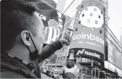  ?? RICHARD DREW/AP ?? Coinbase employee Daniel Huynh holds a bottle of Champagne as he takes a picture Wednesday outside the Nasdaq MarketSite in New York’s Times Square. The digital currency exchange became a publicly traded company earlier this week.