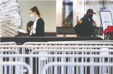  ?? KEVIN KING / POSTMEDIA NEWS ?? Masked workers and a police officer at the COVID-19 immunizati­on centre super site in Winnipeg on Wednesday.