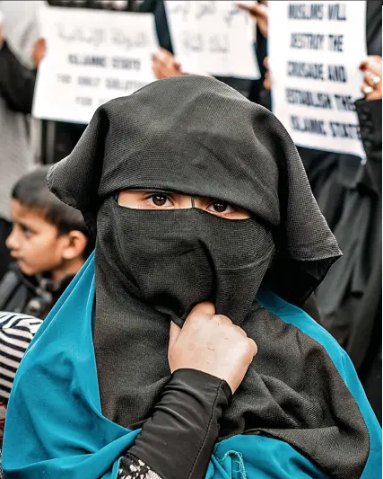  ?? Y M A L : e r u t c i P ?? Indoctrina­ted: A girl in a burka at a Choudary rally at Central London Mosque in front of placards reading: ‘Muslims will destroy the crusade and establish the Islamic State’