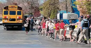  ?? Jonathan Mattise/Associated Press ?? Children from The Covenant School, a private Christian school in Nashville, Tenn., hold hands as they are taken to a reunificat­ion site at the Woodmont Baptist Church after a deadly shooting at their school on March 27.