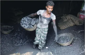  ?? — Reuters ?? A worker carries coal in a basket in a industrial area in Mumbai. India’s growth slowed to 7.1 per cent following the government’s shock move last November to ban most of the currency in circulatio­n.